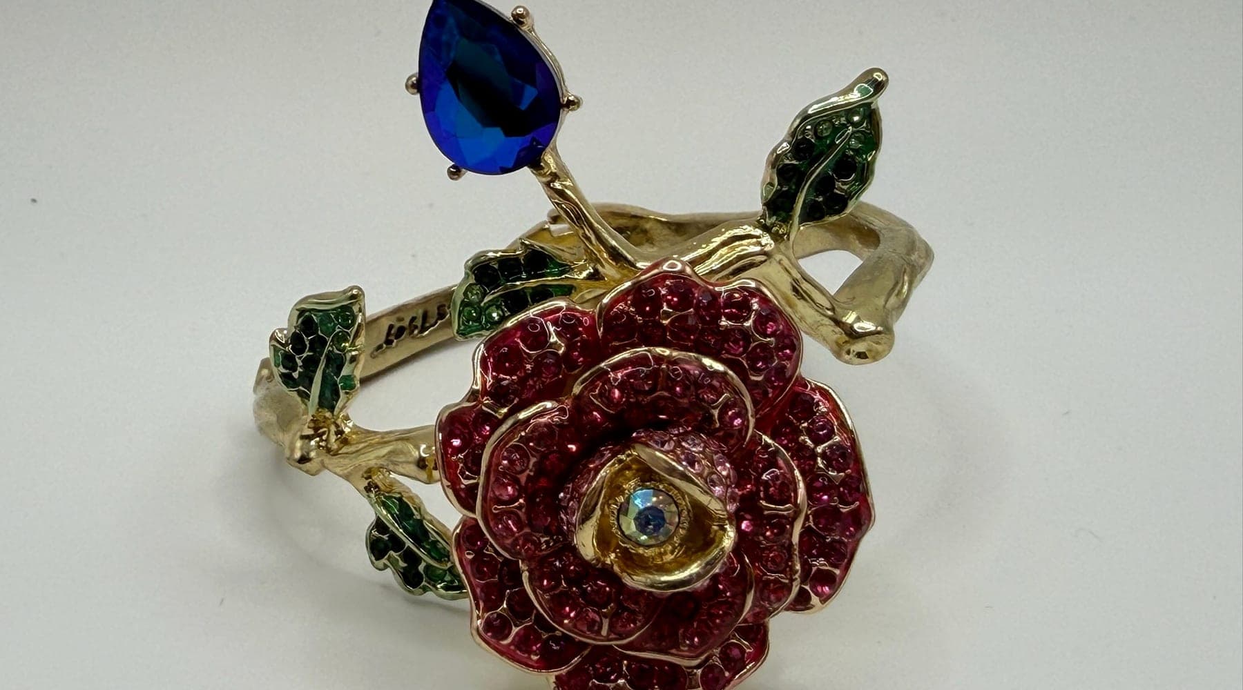 A rhinestone rose hinged bracelet, photographed in hand